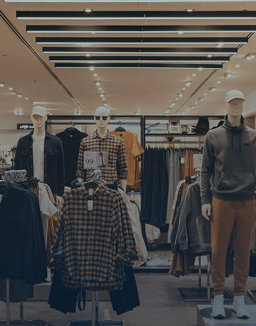 Three mannequins dressed in casual men's clothing displayed in a well-lit retail store.