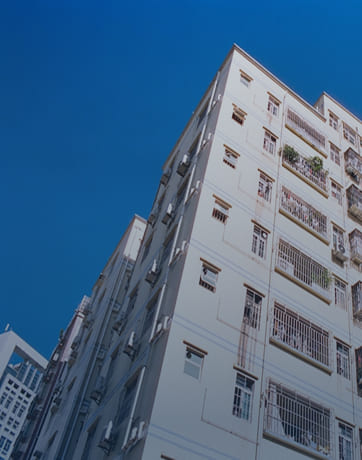 Low-angle view of a white residential building under a clear blue sky.