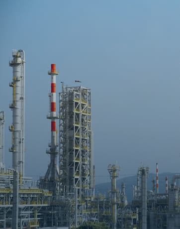 Industrial complex with tall towers and chimneys against a clear blue sky.