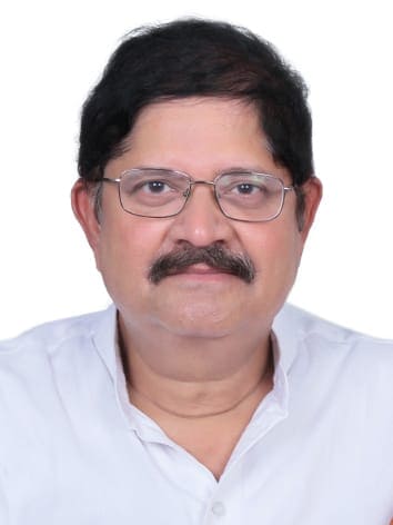 Portrait of a middle-aged man with glasses, mustache, and short black hair wearing a white shirt.