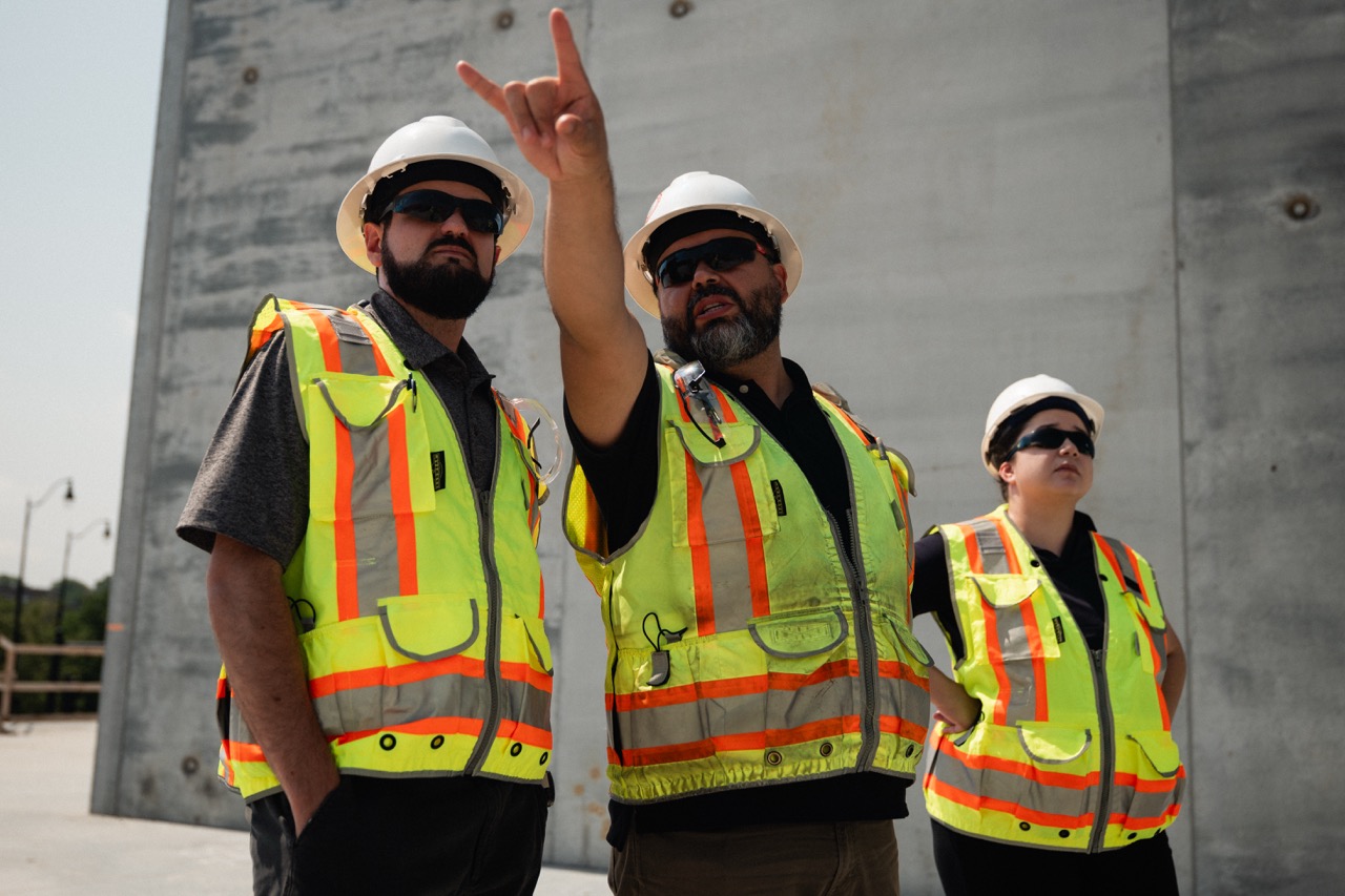 Encore team members in hard hats and high-visibility gear looking upward.