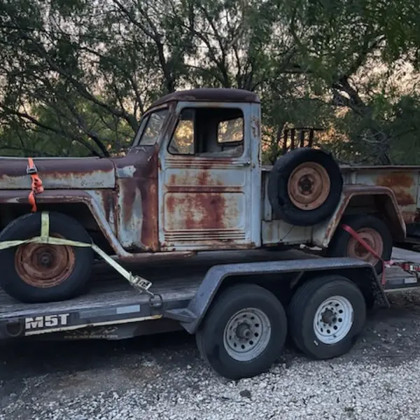 Barn-find Willys pickup truck strapped to a trailer for a restoration appraisal
