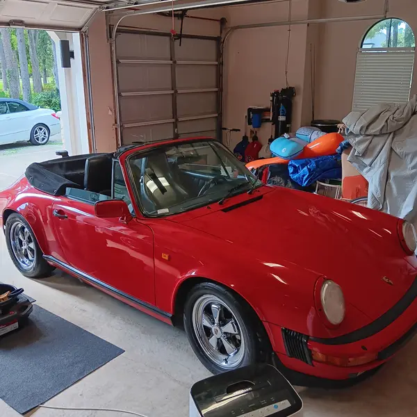 Red Porsche 911 Carrera cabriolet in a garage during a pre-purchase appraisal