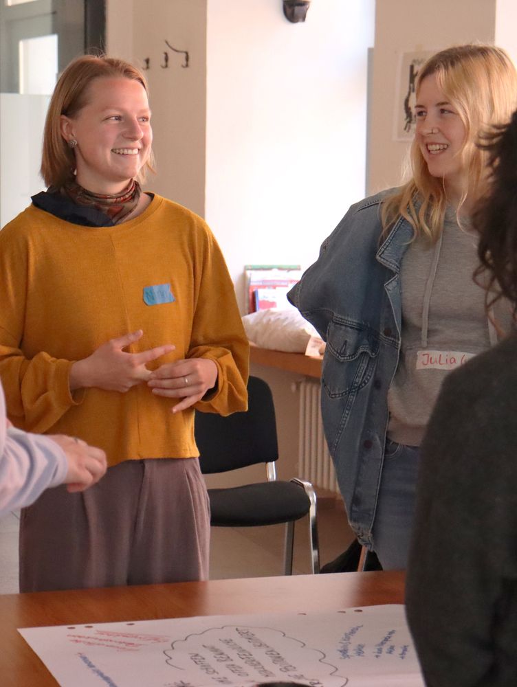 Zwei Studierende im Gespräch, eine im gelben Pullover