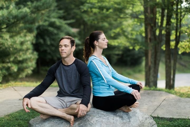 parents-practicing-SKY-Breath-Meditation-sitting-on-a-rock-outside