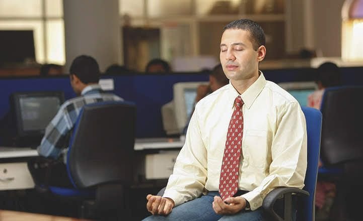 A man meditating in his workplace is using a great stress reliever.