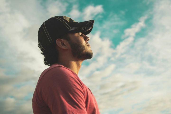 A man standing outside is taking deep breaths.
