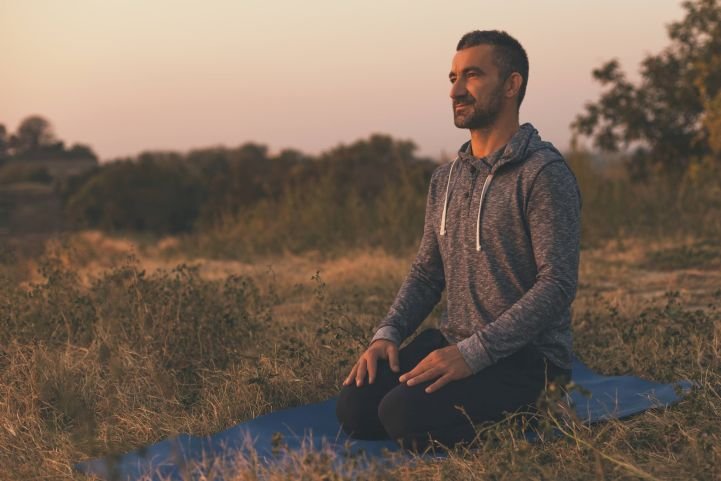 A man sitting on a yoga mat in nature and silence.