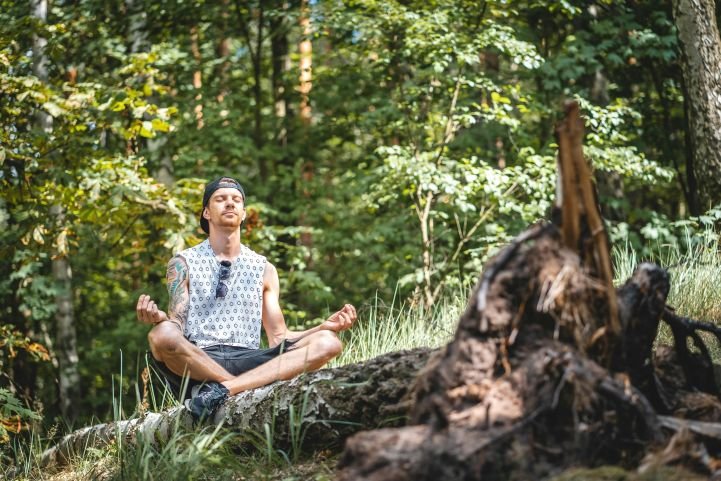 A man forest bathing and meditating in a wooded area.