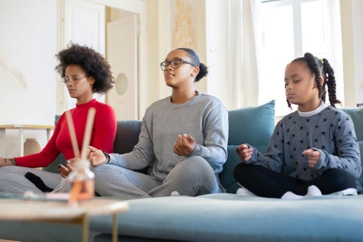 A mom and her daughters practicing breathwork together.