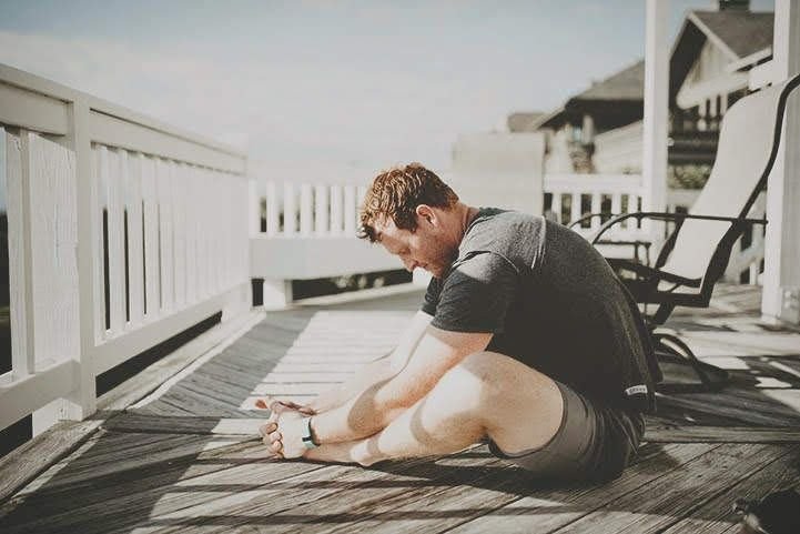 After a workout, a man practices the butterfly pose, encouraging relaxation of the hips.