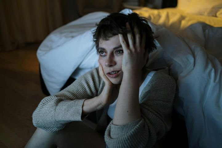 Insomniac sitting in the glow of blue light from a TV.