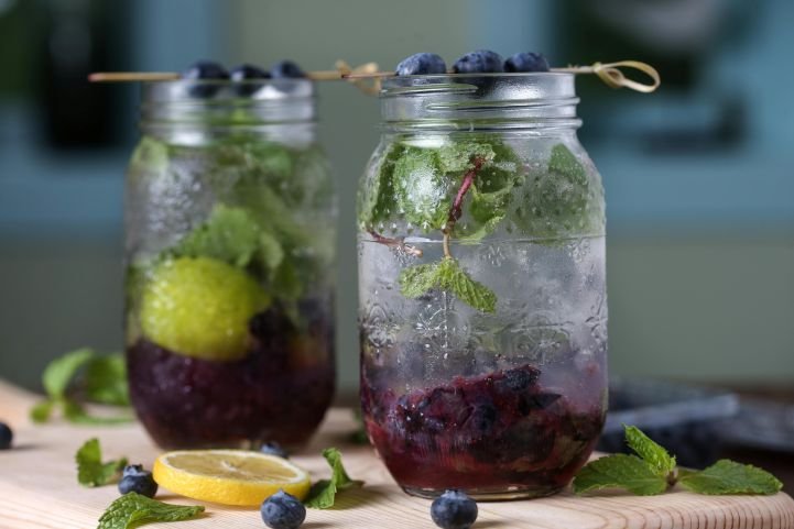 Two jars of a sparkling berry mocktail with mint.