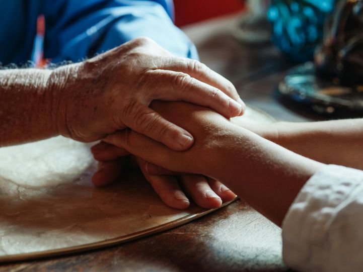 Two people with stacked hands symbolizing compassion.