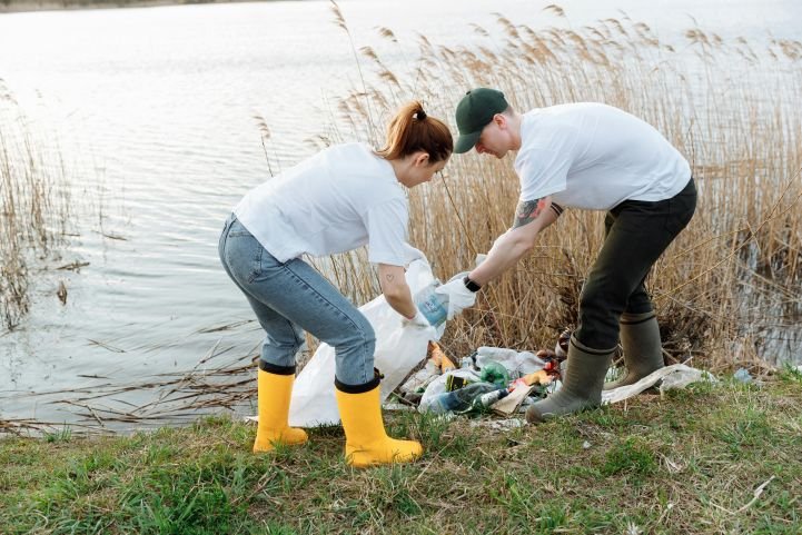 A woman and a man cleaning up trash at a lake as seva service.