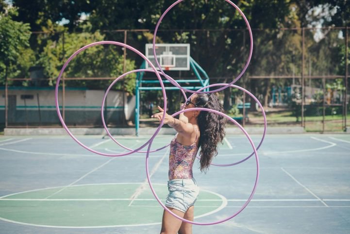 Young woman staying focused during healthy stress while juggling multiple hula hoops.