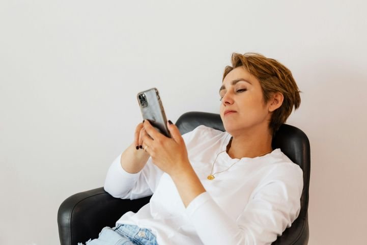 Woman scrolling social media on her phone and experiencing emotional fatigue.