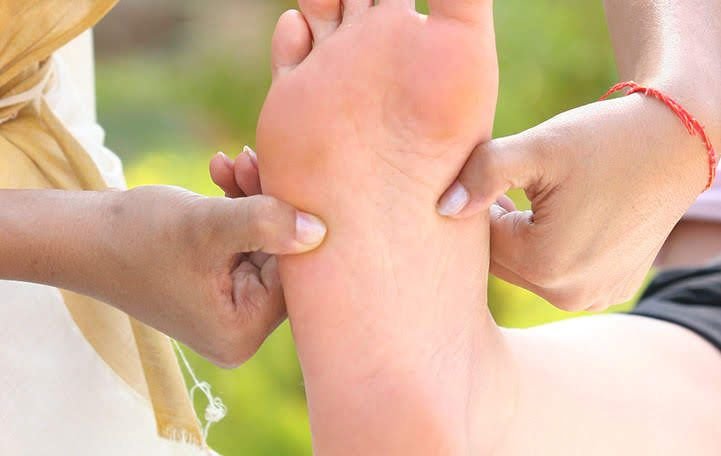 A Marma practitioner practicing Ayurvedic Marma massage on a foot.