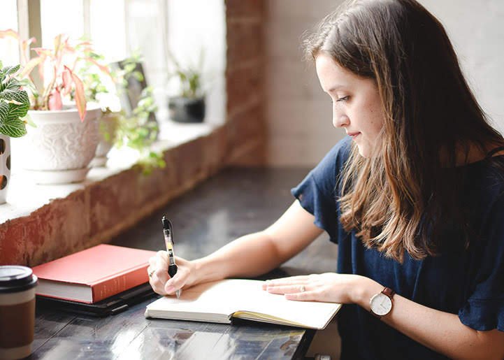 A woman journaling, representing reflective questions for gaining a new perspective.