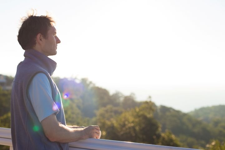 Man experiencing the present moment as he looks out over a natural setting.
