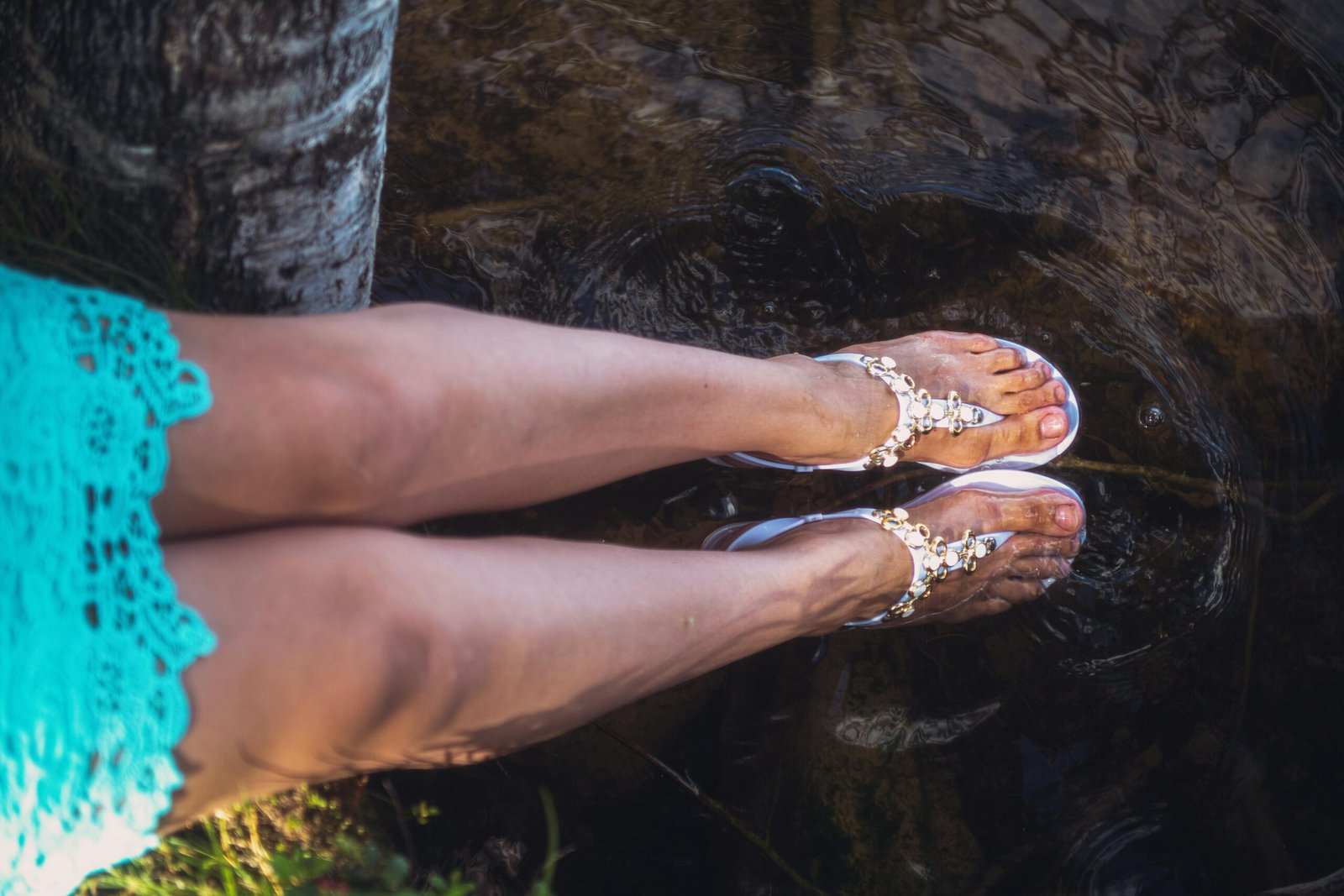 Sandaled feet immersed in a natural body of cool water.