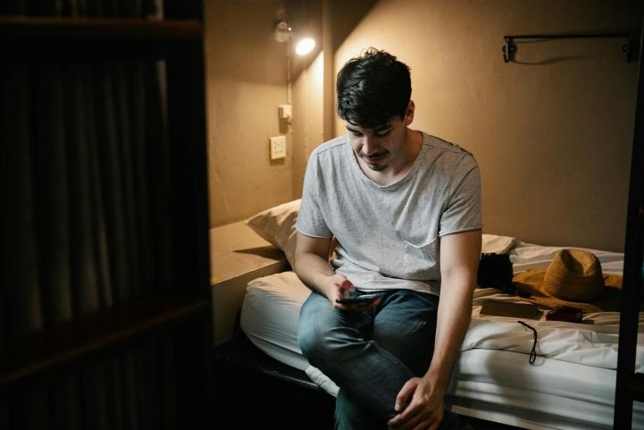 Man sitting on the edge of his bed, feeling too anxious to sleep.