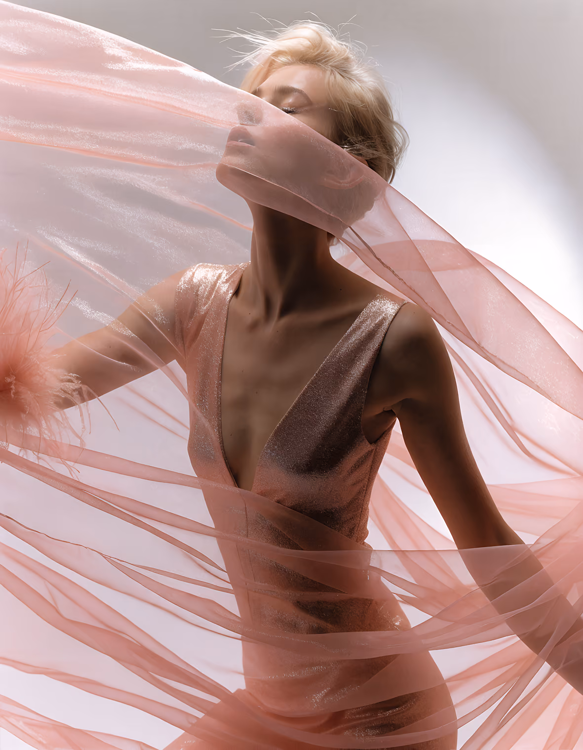 Woman in a shimmering pink dress wrapped in flowing sheer pink fabric with closed eyes.