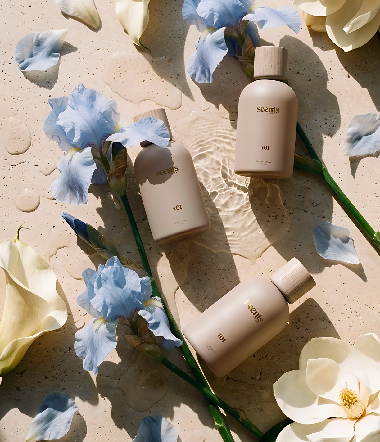 Three beige bottles labeled "scents 401" on a stone surface with blue and white flowers around them.