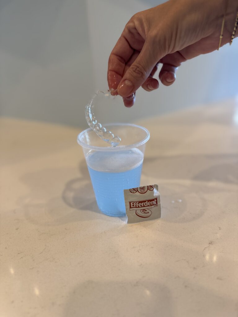 Clear aligners soaking in a glass cup