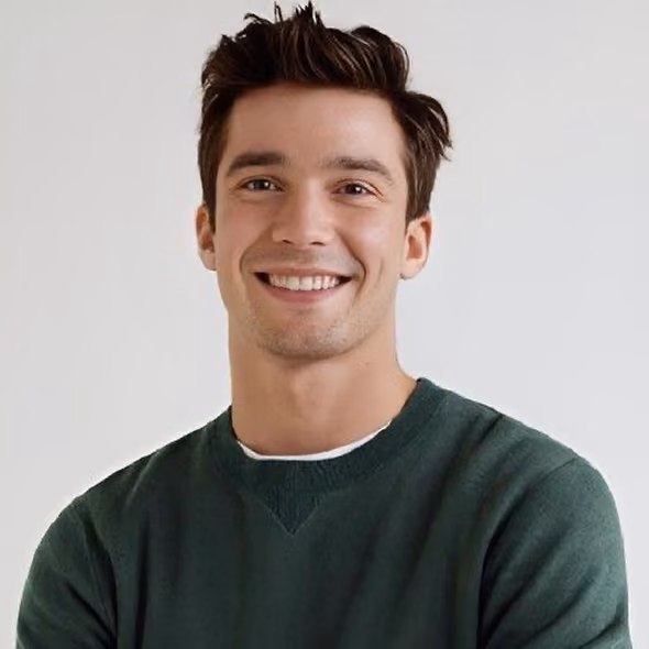 Smiling young man with short brown hair wearing a dark green sweater against a plain light background.