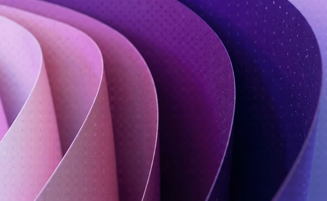 Close-up of layered curved sheets of paper or material in shades of pink, purple, and violet with a dotted texture.