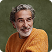Smiling older man with gray hair and beard wearing an orange sweater.