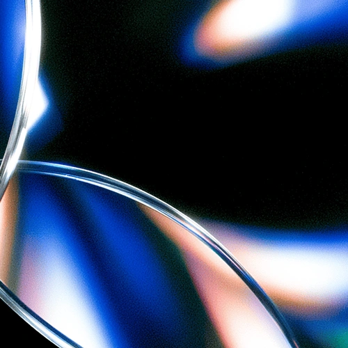 Abstract close-up of transparent curved glass with blue and orange light reflections.
