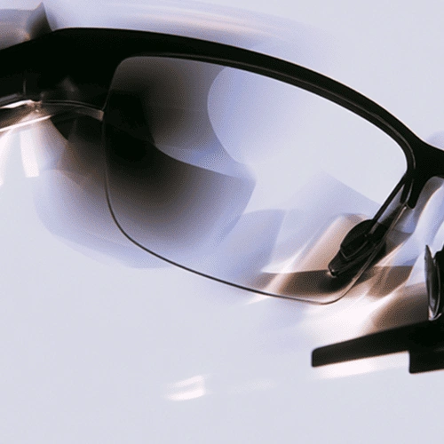 Close-up of black-framed eyeglasses with reflections on the lens against a light background.
