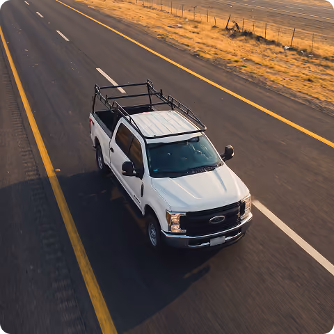 White pickup truck with a roof rack driving on a highway