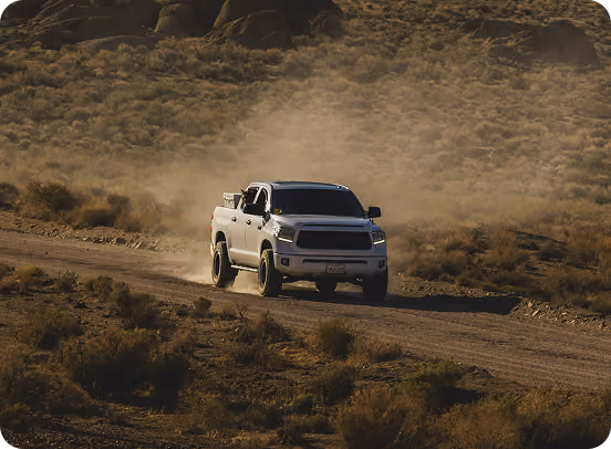 Pickup truck driving on a dirt road kicking up dust