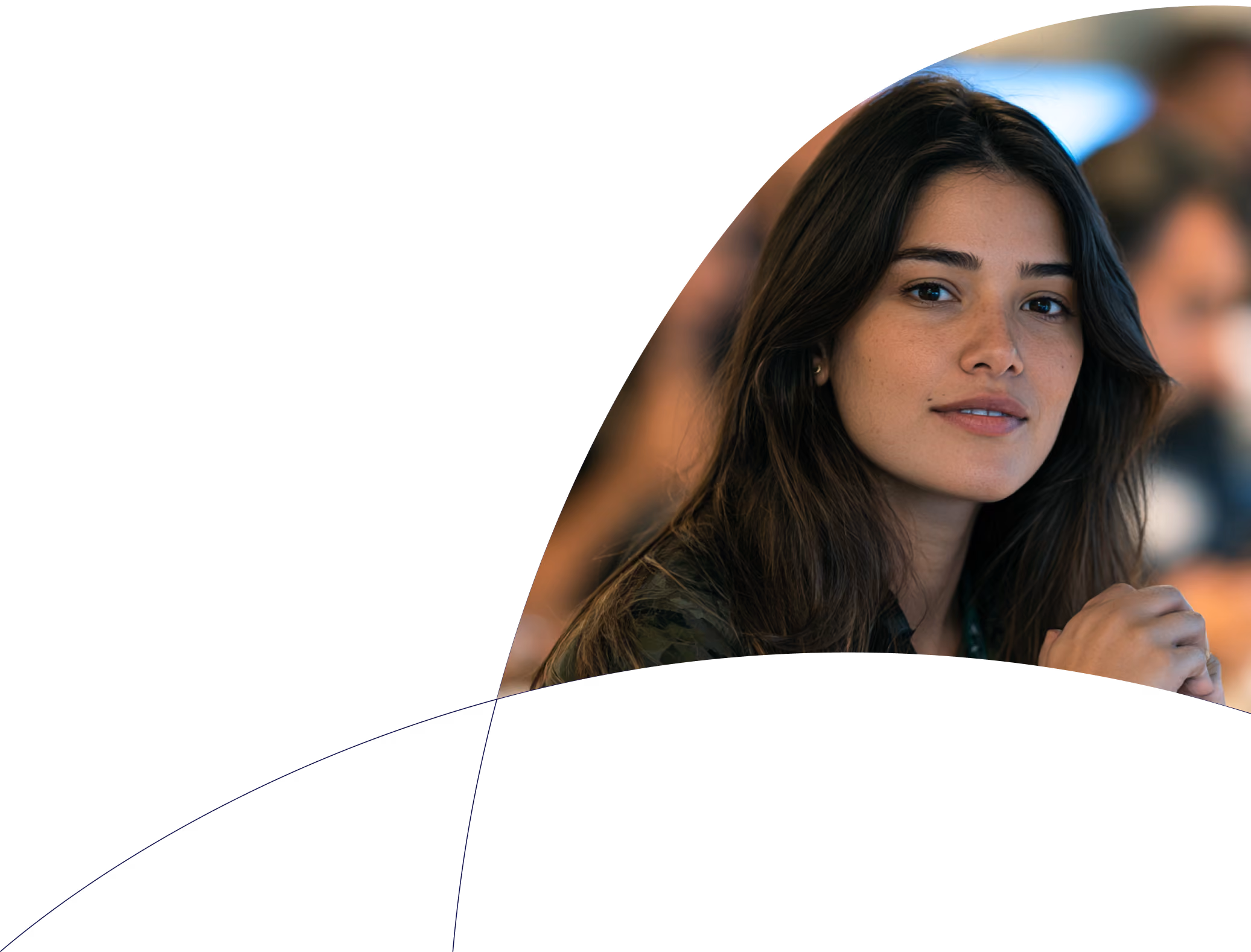 Jovem mulher de cabelos castanhos escuros e pele clara, olhando para frente com expressão calma e ligeiro sorriso, em ambiente interno com fundo desfocado.