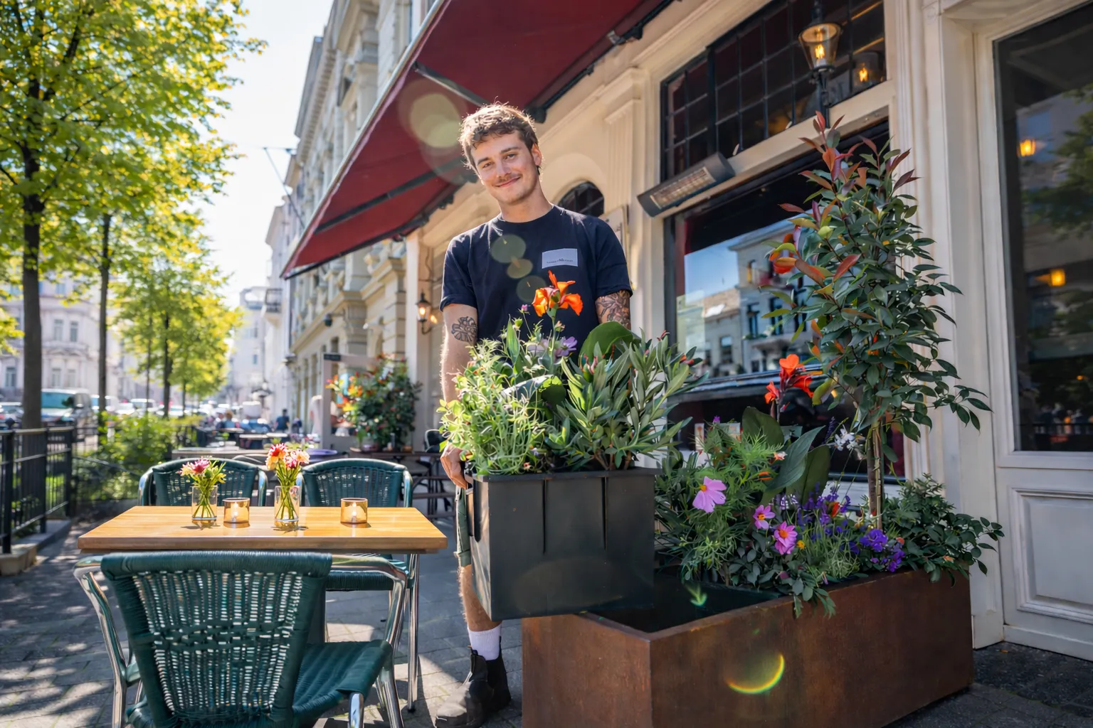 Uitbater op zijn stadsterras tussen cortenstalen plantenbakken met zomerbloeiers en een boompje