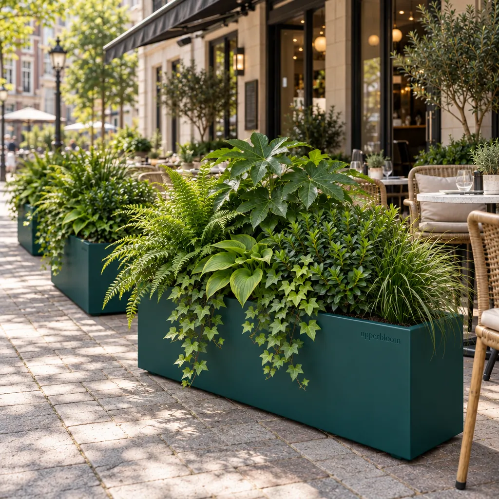Rij donkergroene plantenbakken met varens, hosta en klimop langs een restaurantterras