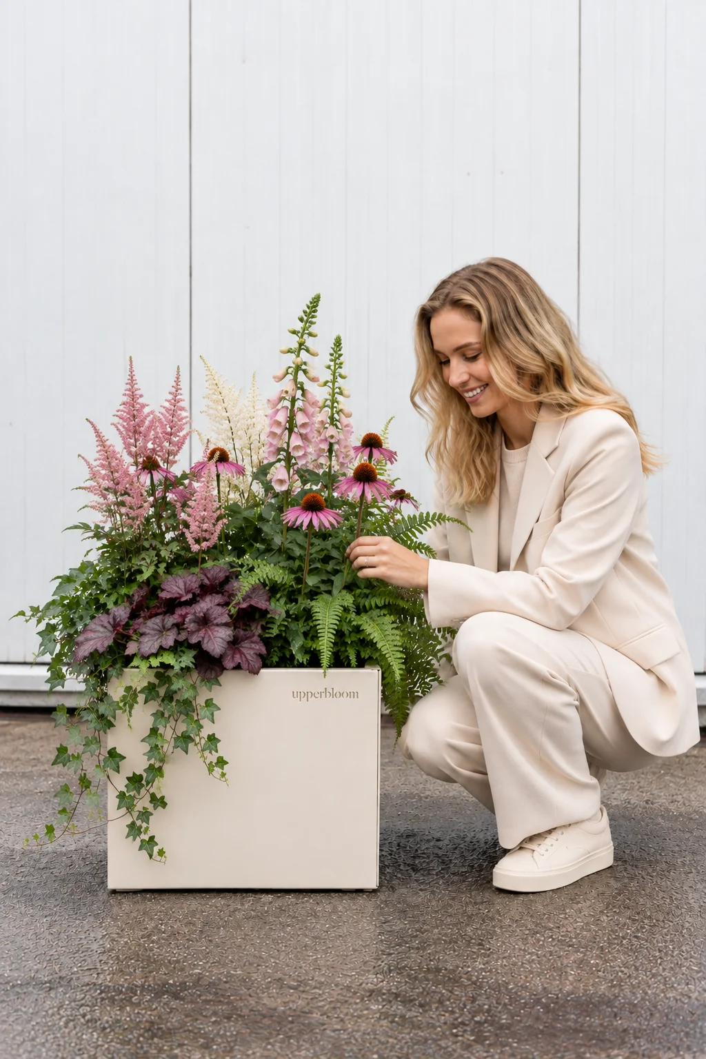Vrouw bekijkt een vierkante plantenbak met astilbe, echinacea, heuchera en klimop