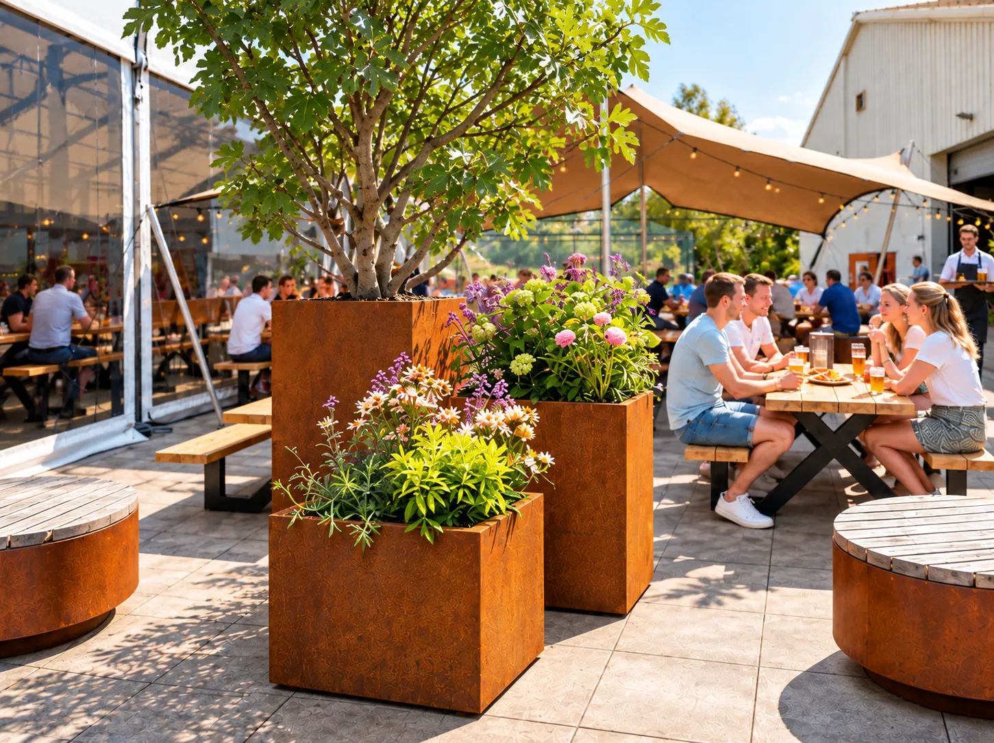 Cortenstalen plantenbakken in verschillende hoogtes met een boom en zomerbloeiers, tussen ronde zitplekken en picknicktafels