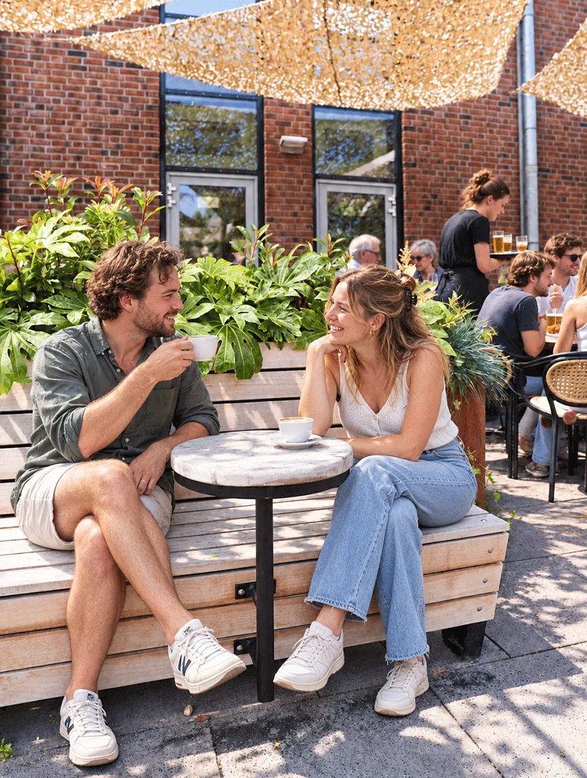 Stel drinkt koffie op houten terrasbank naast plantenbak met grote bladplanten