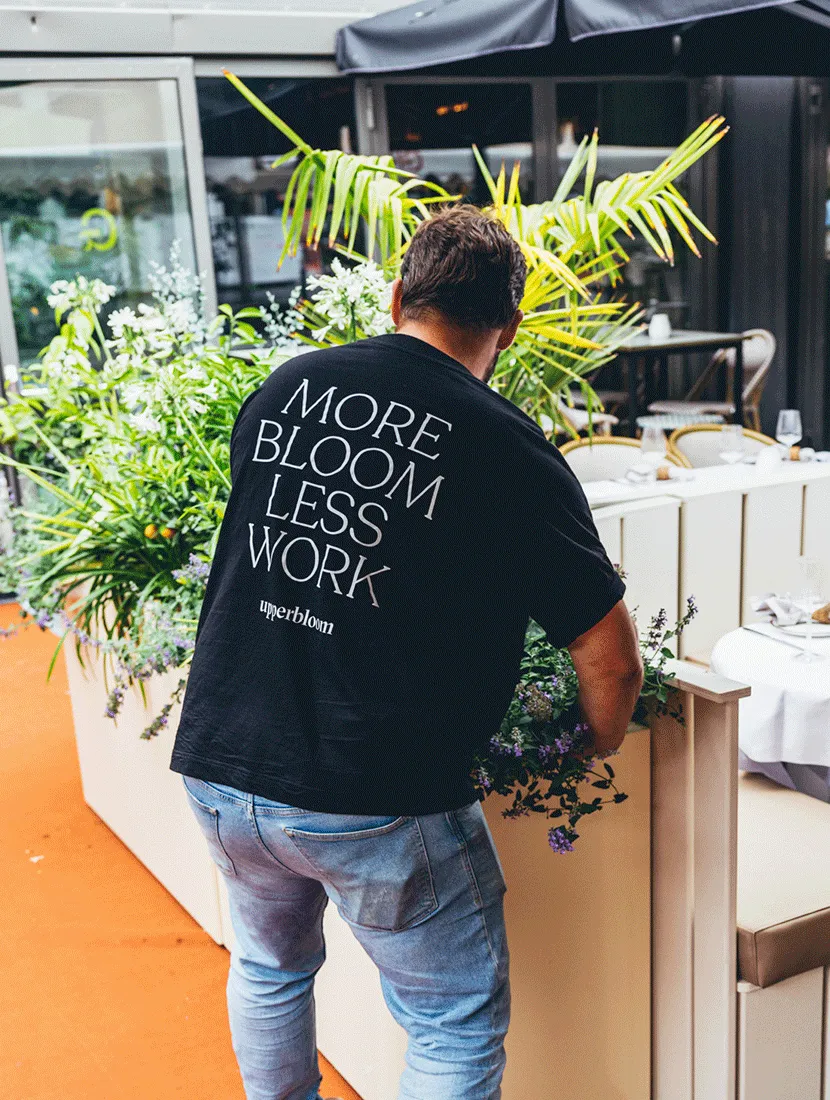 Medewerker van Upperbloom met 'More bloom, less work' op zijn shirt werkt aan de beplanting van het terras