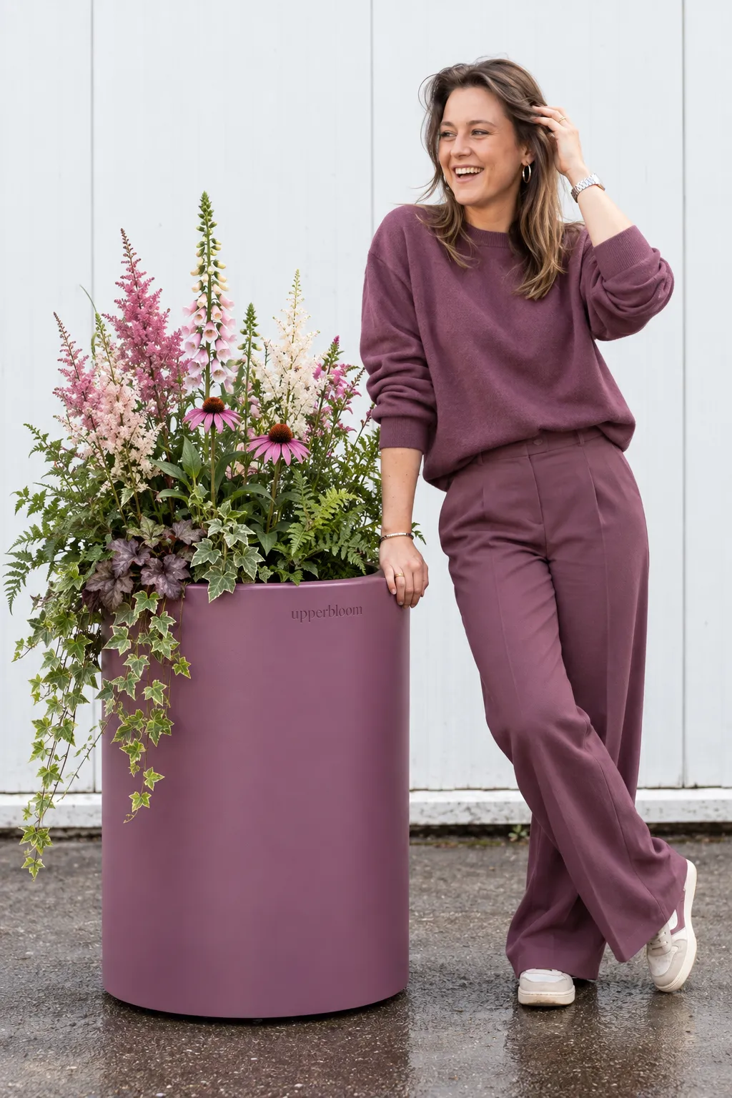 Vrouw naast hoge aubergine plantenbak met vingerhoedskruid, astilbe, echinacea en klimop