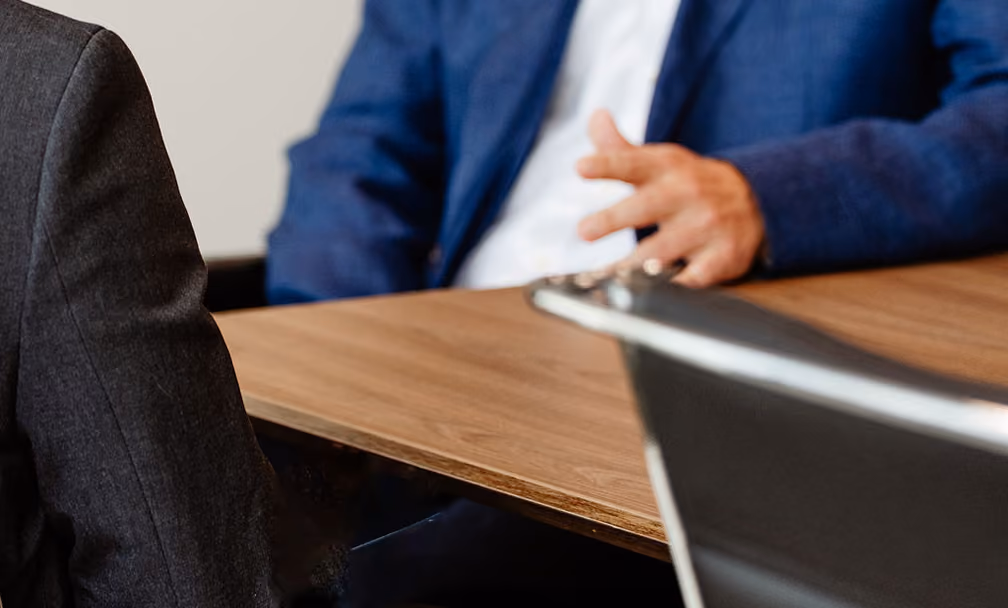 Two people seated across a meeting table