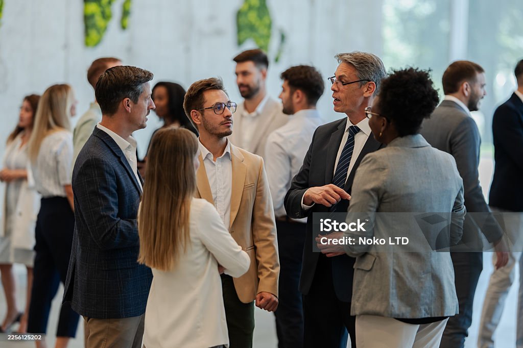 Group of diverse business people talking and networking in a modern office setting.