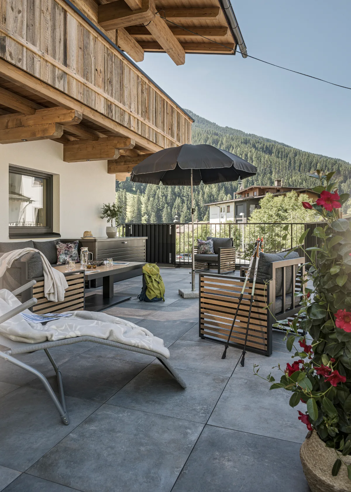 Sonnenterrasse des Ferienhaus Evelyn mit Loungemöbeln, Sonnenschirm und Blick auf die bewaldeten Berge