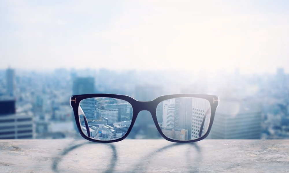 Corrective eyeglasses resting on a ledge overlooking a city skyline