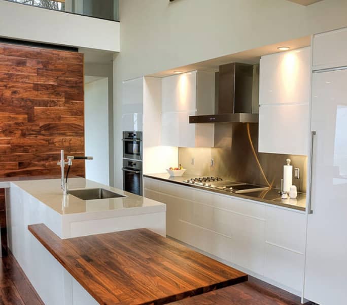 A modern white kitchen combining high gloss acrylic fronts and natural materials.
