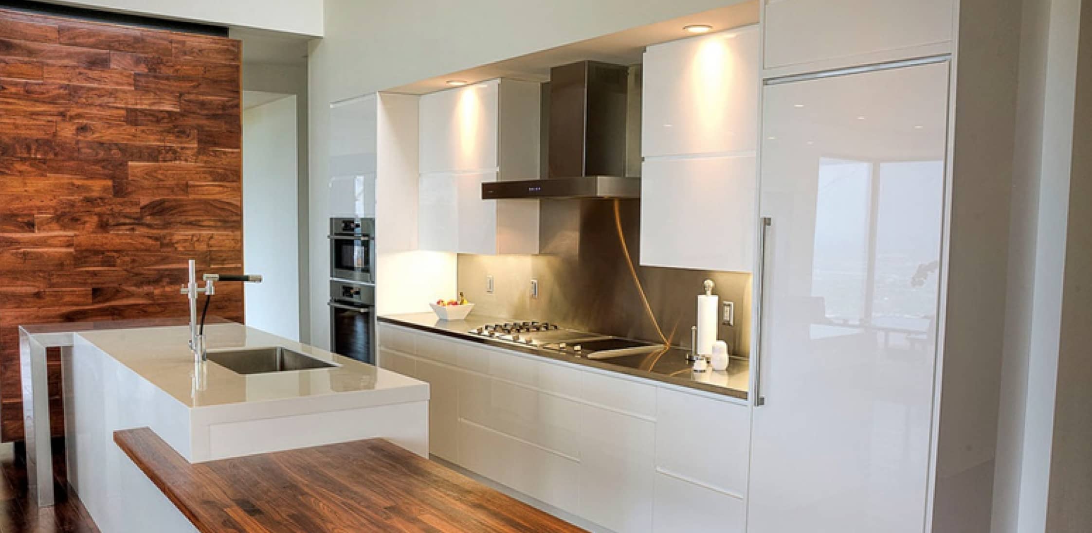 A modern white kitchen combining high gloss acrylic fronts and natural materials.